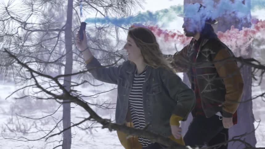 A man and woman run with colorful smoke coming out of canisters