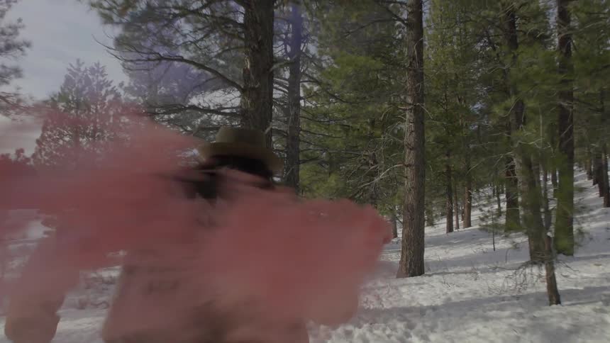 A man running through a snowy forest with a smoking flair