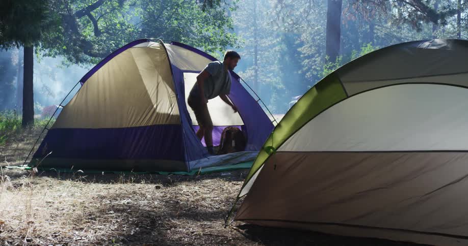 Man comes out of a tent and stretches his arms