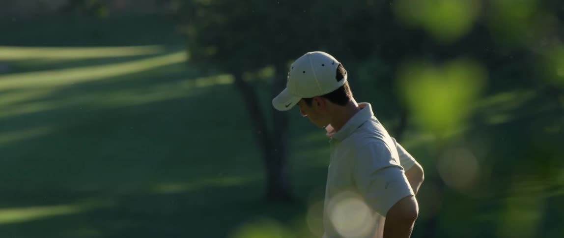 A man stands on a golf course with his hands on his hips