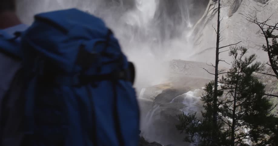 People hiking on a trail by a waterfall