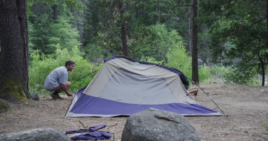 Two men taking down a tent in the woods