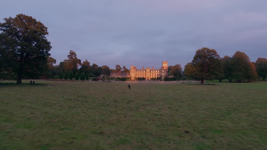 A white man walks towards a castle on a giant estate
