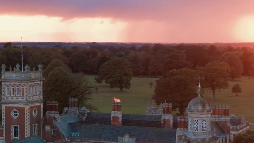 Fire leaps out of a chimney on the roof of large castle estate