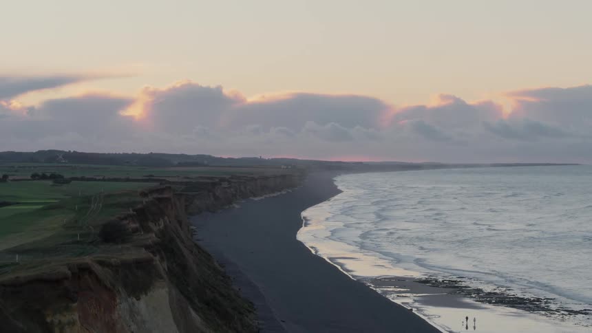 Two people walk along the shore with their dog