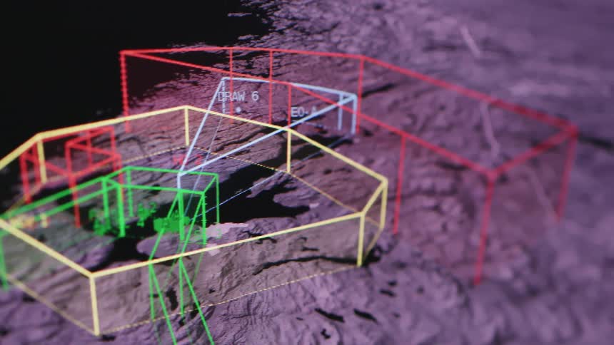 A computer monitor displaying rocky terrain with computer generated shapes projected onto it