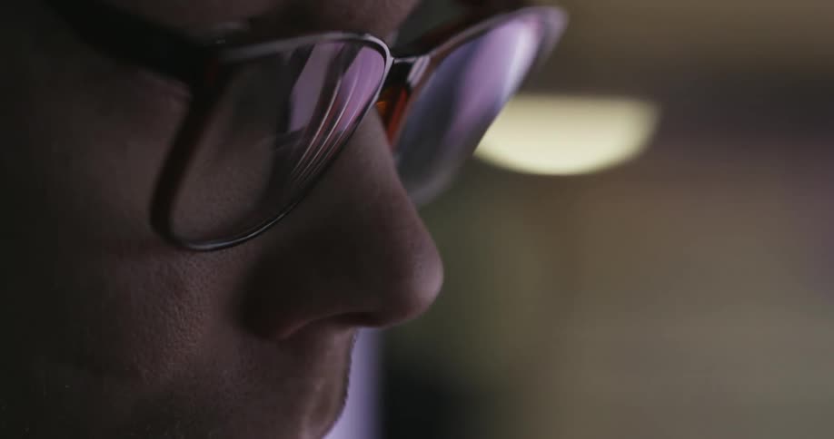 A white man wearing glasses watches something in a room