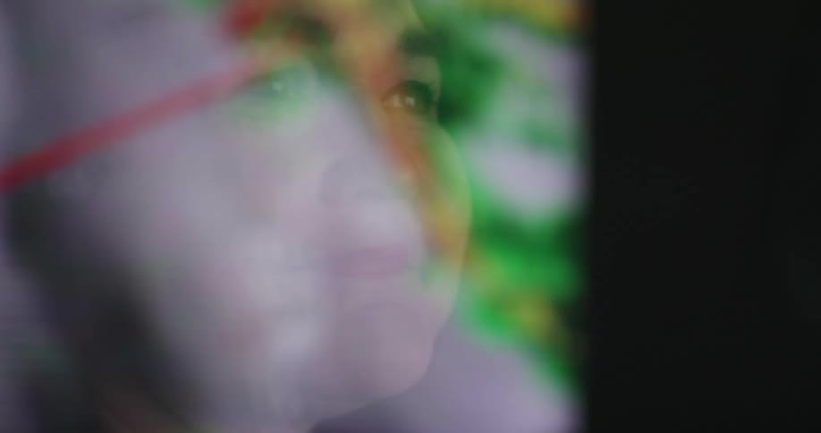 The reflection of a computer screen on a womans face as she looks at the weather radar