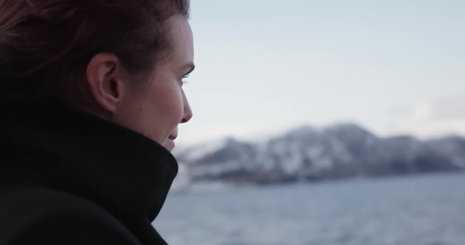A woman looks at the mountains from the traveling boat