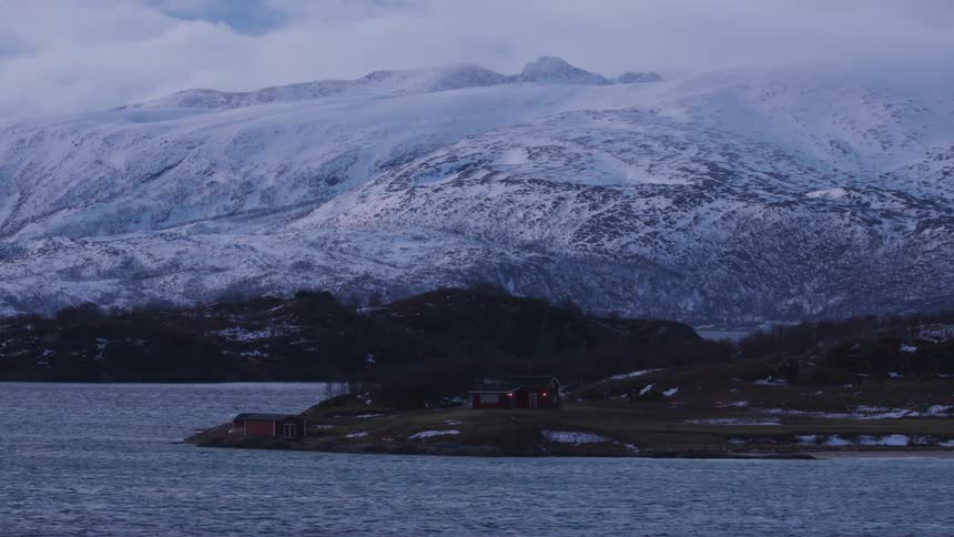 The mountain by the shore is covered in ice and snow