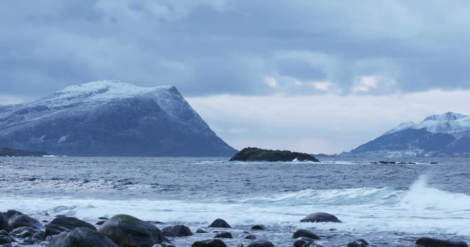Waves rolling in to the shore in front of mountains