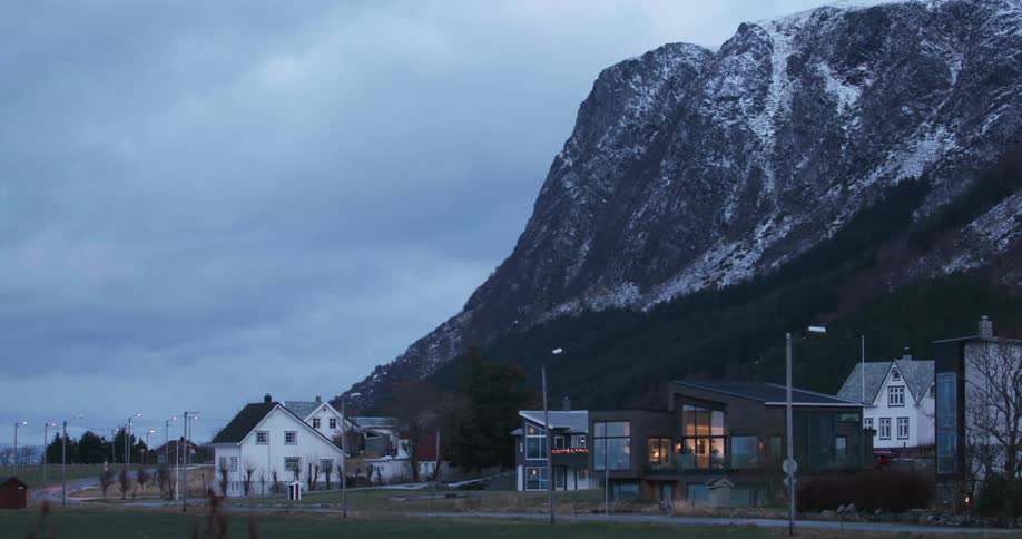 Homes and a road at the base of a snow dotted mountain ridge