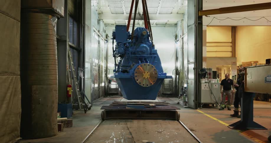Two men watch as a large piece of equipment is moved