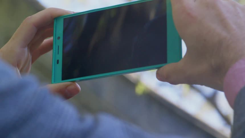 A man holds his cell phone up to take a picture