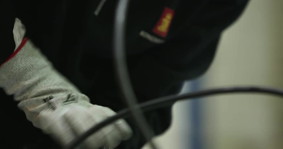 Woman wearing work gloves and safety goggles twists an allen wrench