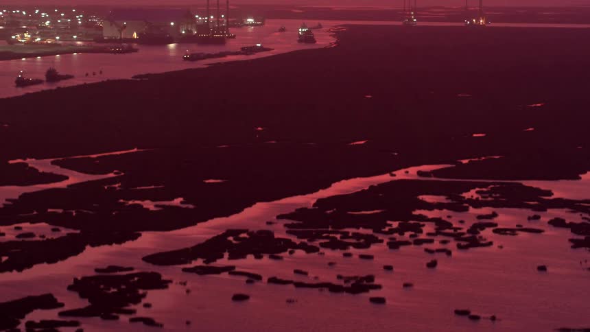 Barges and boats move on a city coastline near wetlands