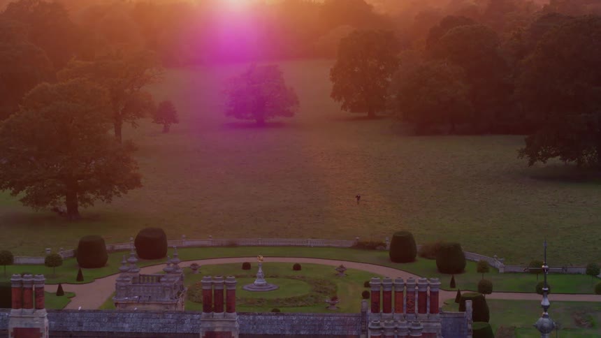 A person walks and stumbles in the lawn outside a large rural estate