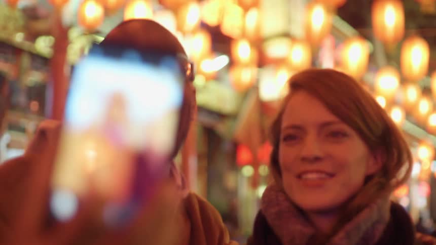 Black man takes a selfie with white woman in the city center at night