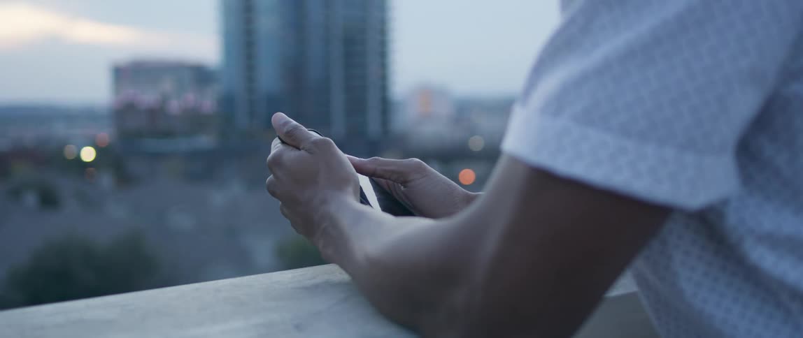 A man stands on a roof top and swipes on his phone