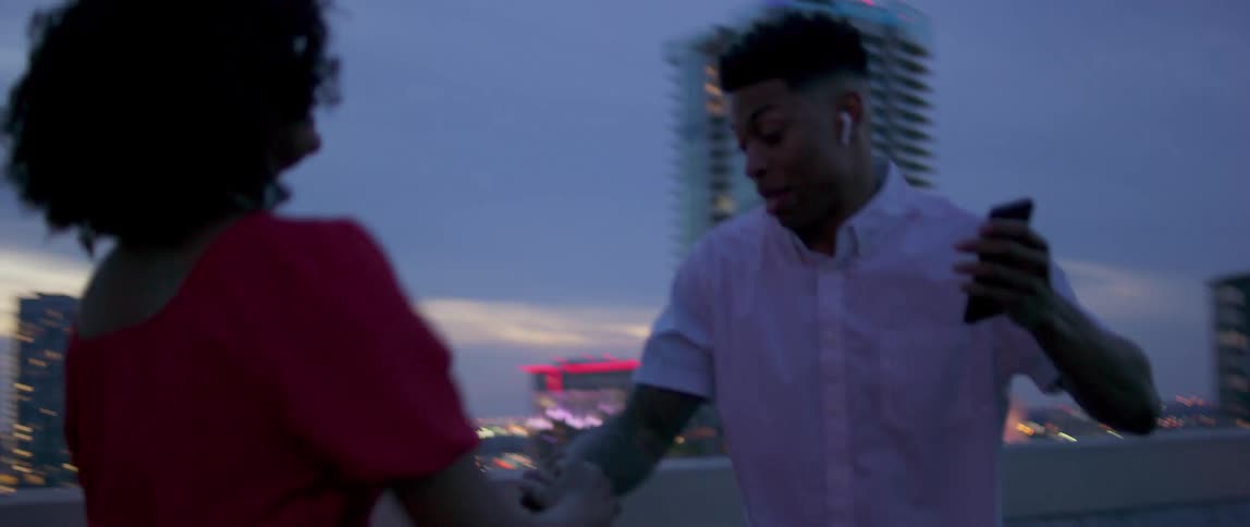 Couple dancing on the roof of a building in the city at sunset