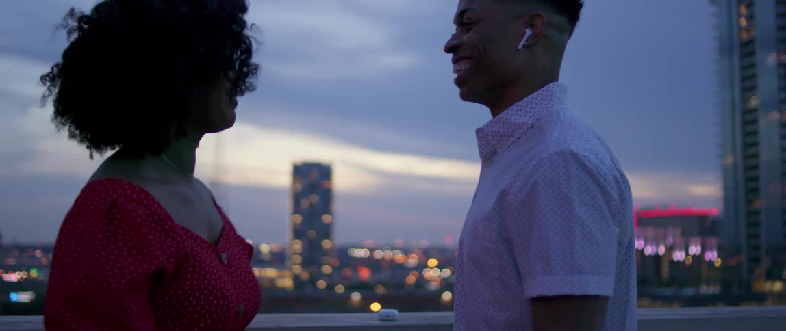 Young couple dance on building roof top at sunset