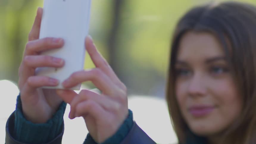 Pretty female taking a selfie on cell phone outdoors