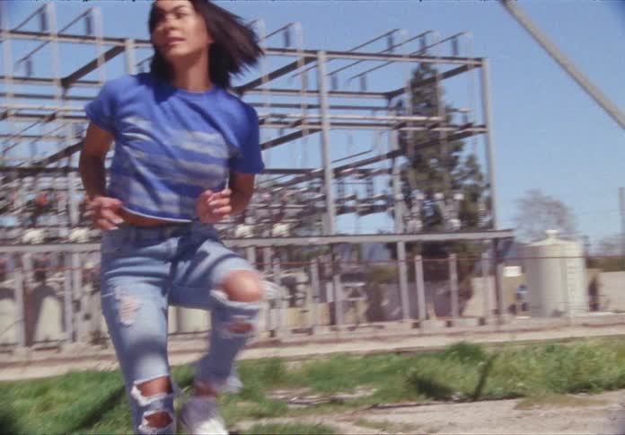 Woman dances outdoors near power station during the day
