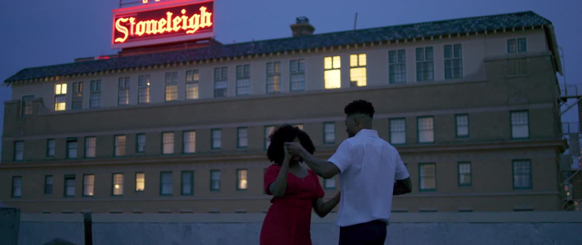 A black couple dance on a rooftop in the city