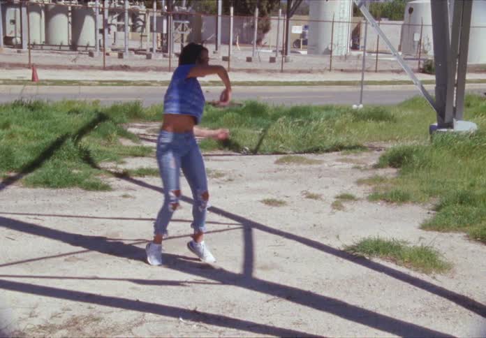 A teenage girl dances next to a road