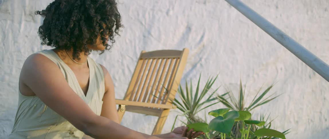 A woman is watering her plant outside