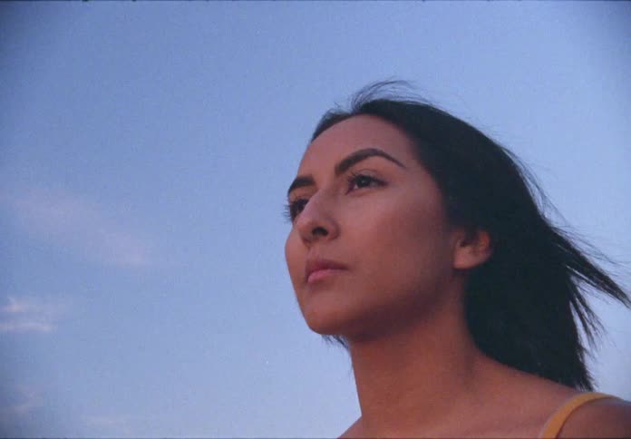 A hispanic teenager outdoors looking around and thinking