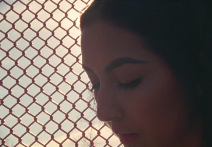 Woman sits on the ground by the wire fence