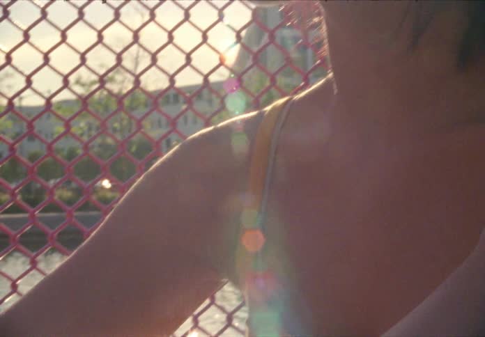Woman sitting on the ground by the wire fence looks ahead
