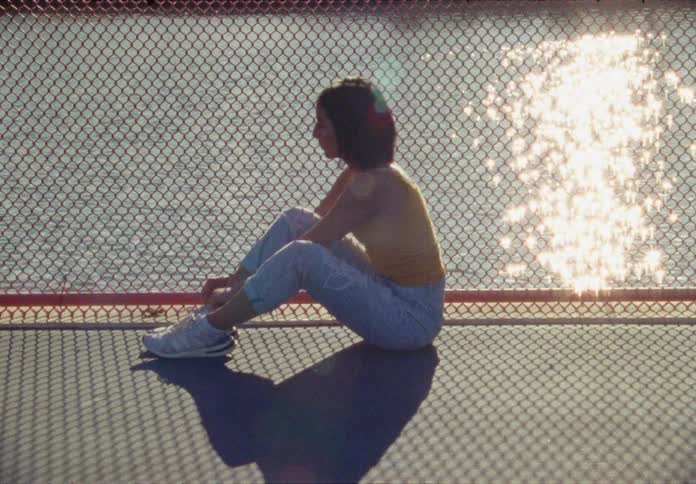 A hispanic teen stretches on pavement by the side of a body of water