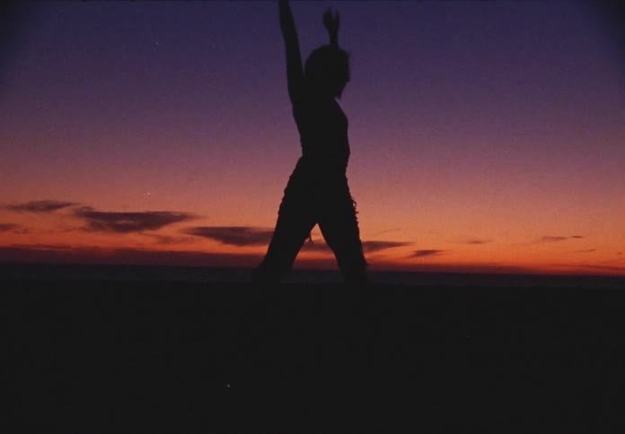 A woman performs a modern dance outside at dusk