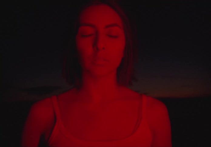 A hispanic teenager bathed in red light outdoors