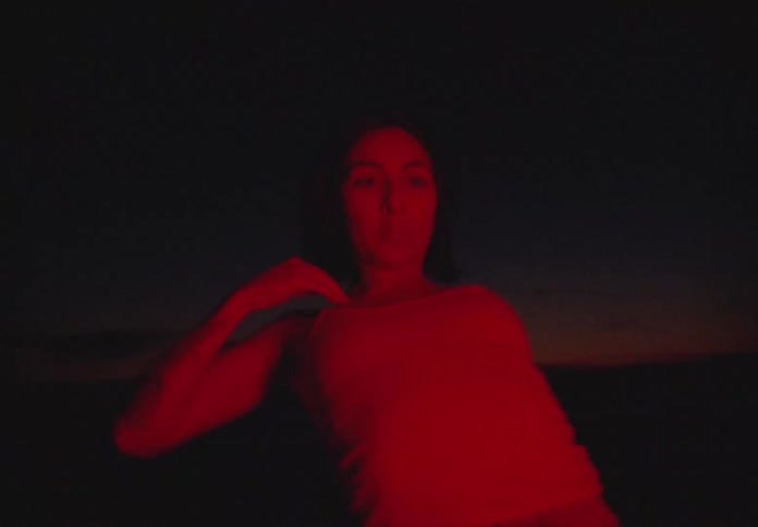 A woman spins and kneels as she does a modern dance outside