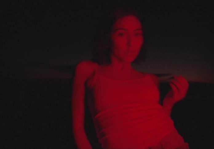 A woman twists and turns as she performs a modern dance outside at night