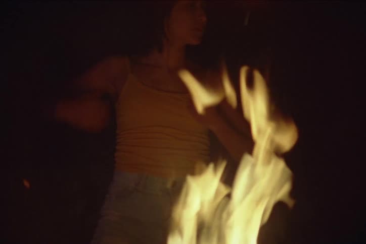 A hispanic girls dances behind a dancing fire