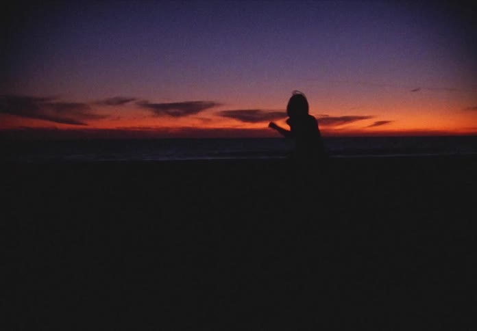 Silhouette of a woman dancing on the beach at night
