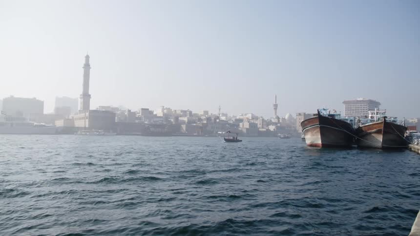 Boats at anchor and sailing in a bay beside a third world city
