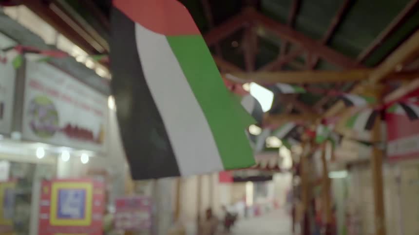 A string of flags hang from a ceiling of a long building