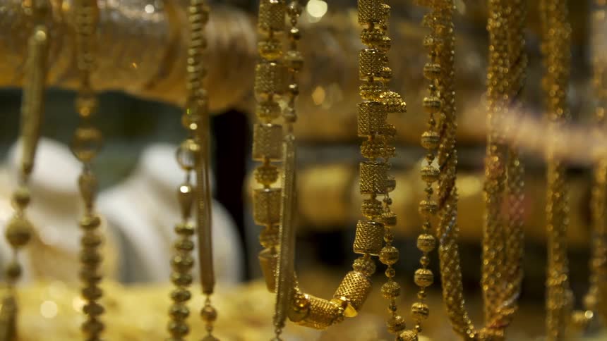 Gold necklaces and other types of jewelry in a display counter at a store