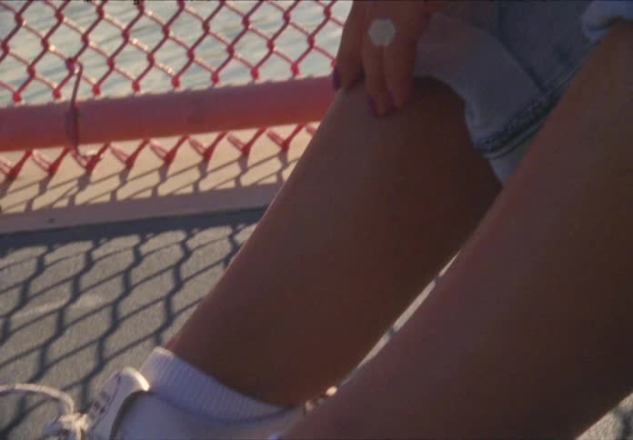 A young woman sits by a red fence outdoors