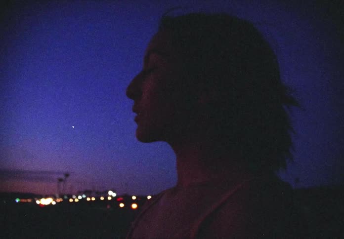 Side view of a woman looking ahead at dusk