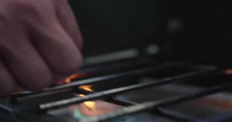 A person strikes a match and lights a grill