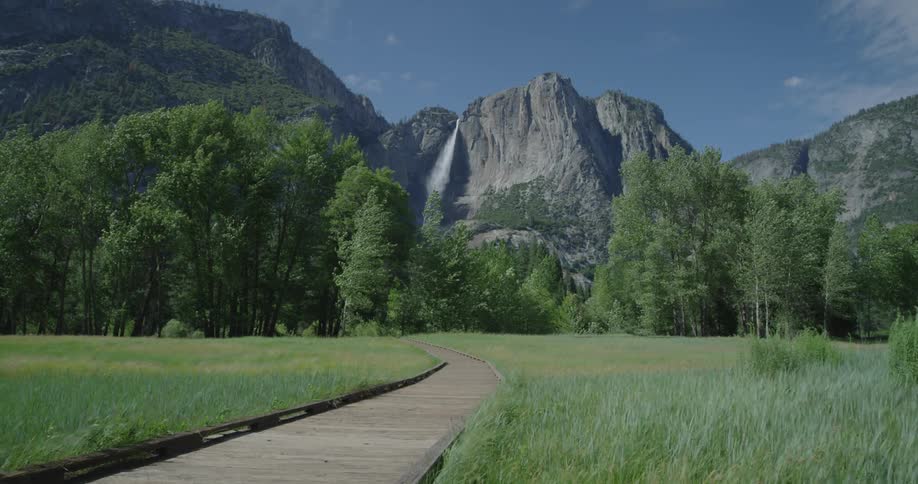 Wind blows grass with mountains in the background