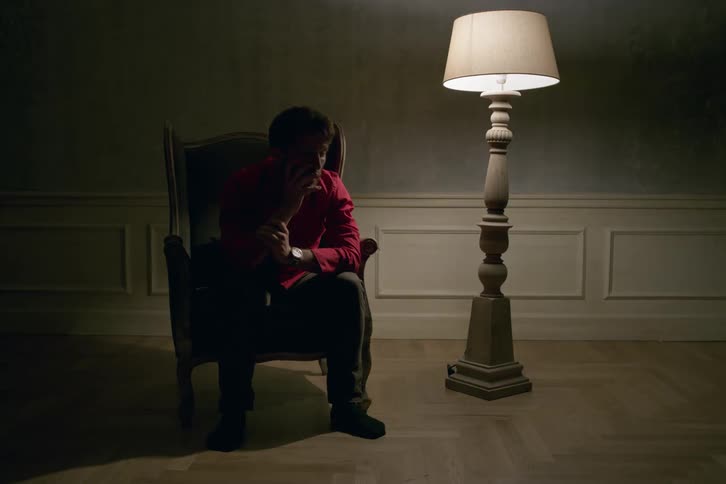 A man sits in a chair with his head in his hands