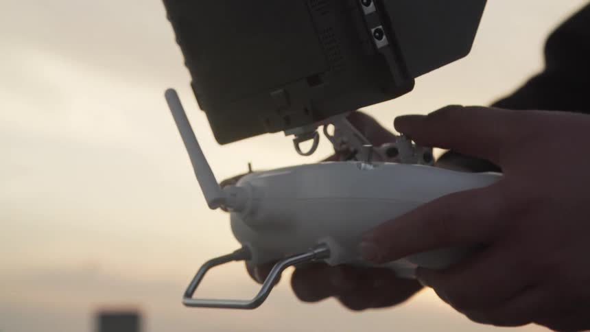 A white man in a jacket with a patch carries a tech device outdoors