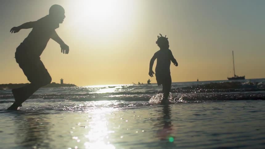 Father and daughter run on the beach